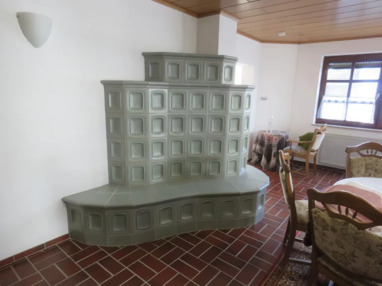 Heller Wohnraum mit großem, modernem Kachelofen als Blickfang, ergänzt durch traditionelle Möbel.