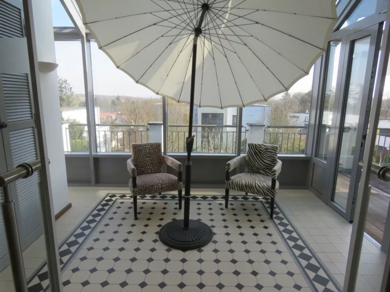 Wintergarten in Bad Soden mit zwei Stühlen unter einem Sonnenschirm und Blick auf die Skyline.