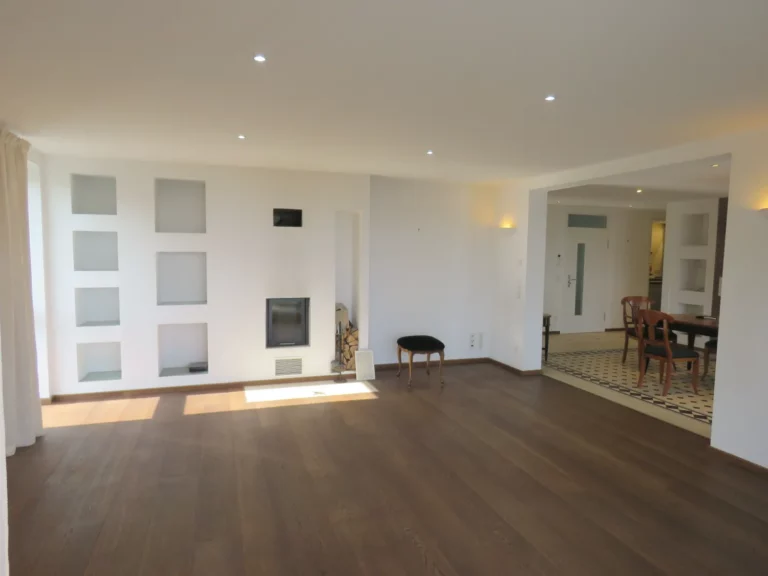 Helles Wohnzimmer mit Holzboden, Kamin und Blick auf den Essbereich in einer Wohnung in Bad Soden.