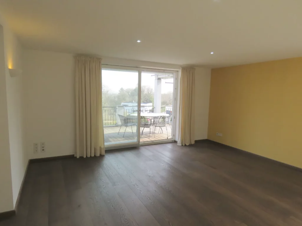 Heller Wohnraum mit dunklem Holzboden und Zugang zum Wintergarten in einer Wohnung in Bad Soden.