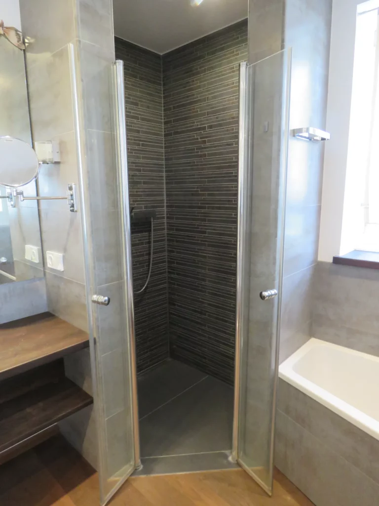 Modernes Badezimmer mit offener Dusche, Waschtisch mit Holzregal und Badewanne in einer 3,5-Zimmer-Wohnung in Bad Soden.