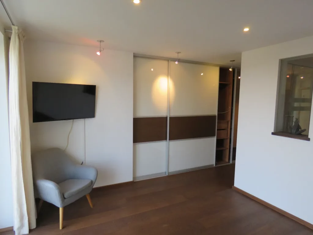 Helles Wohnzimmer in Bad Soden mit TV, Sessel und Einbauschrank in einer luxuriösen 3,5-Zimmer-Wohnung.