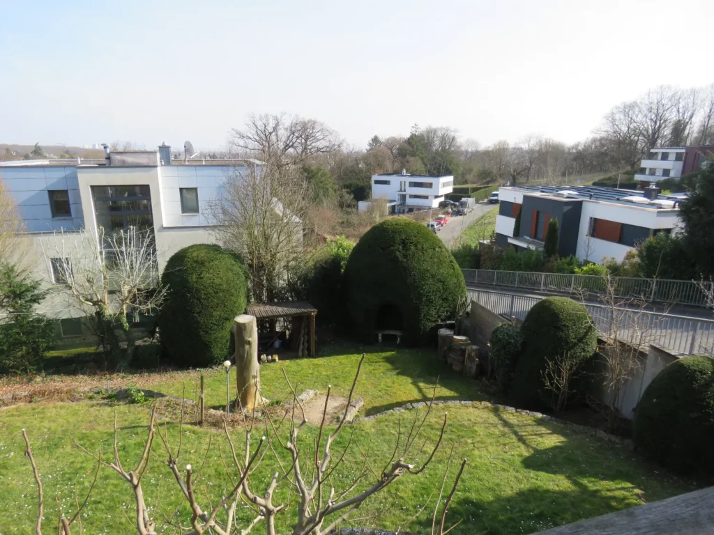 Blick von der Wohnung in Bad Soden auf einen gepflegten Garten mit modernen Häusern im Hintergrund.